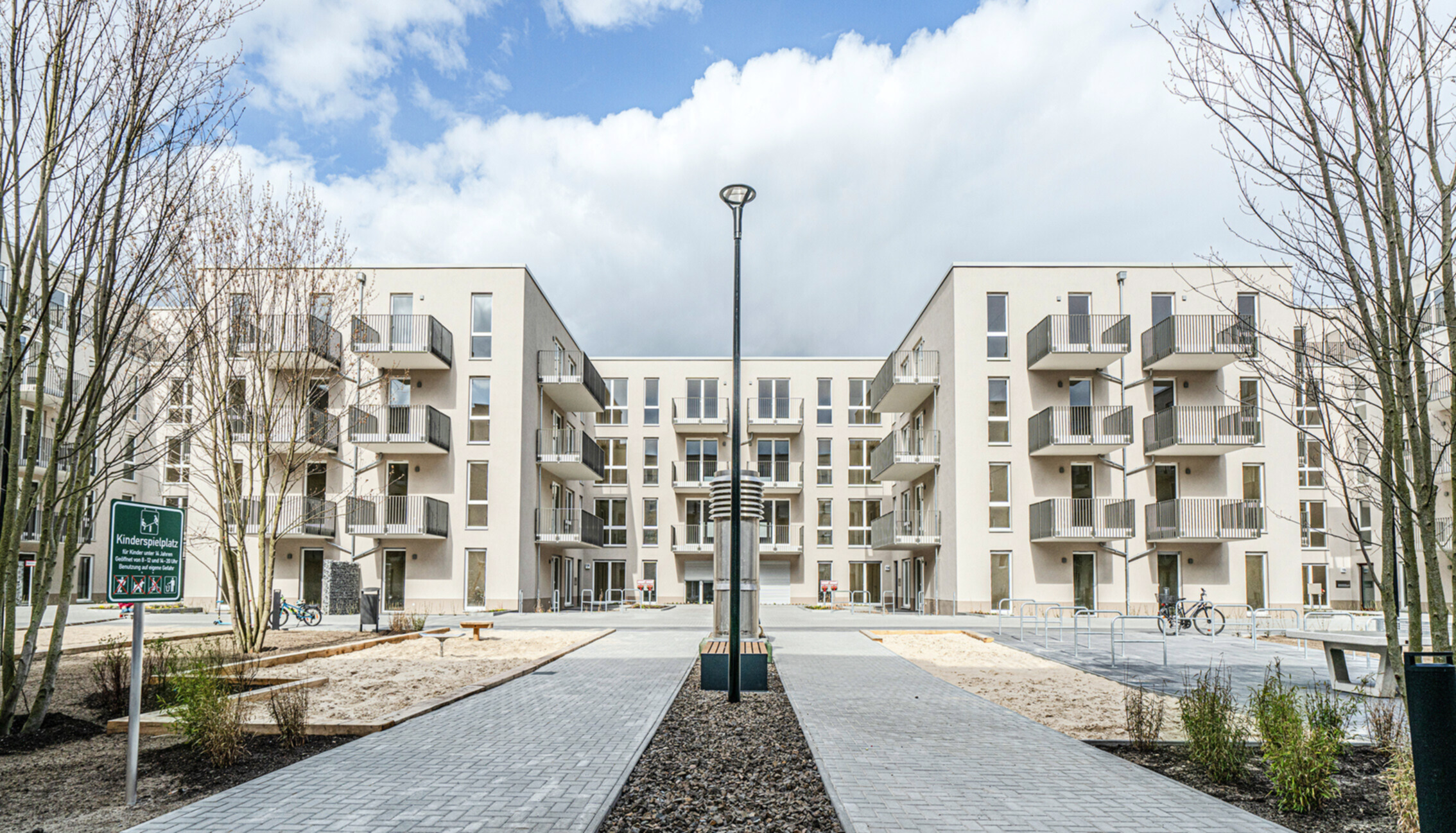 Ein weißer Gebäudekomplex mit Innenhof vom Wohnbauprojekt "CUBIST"