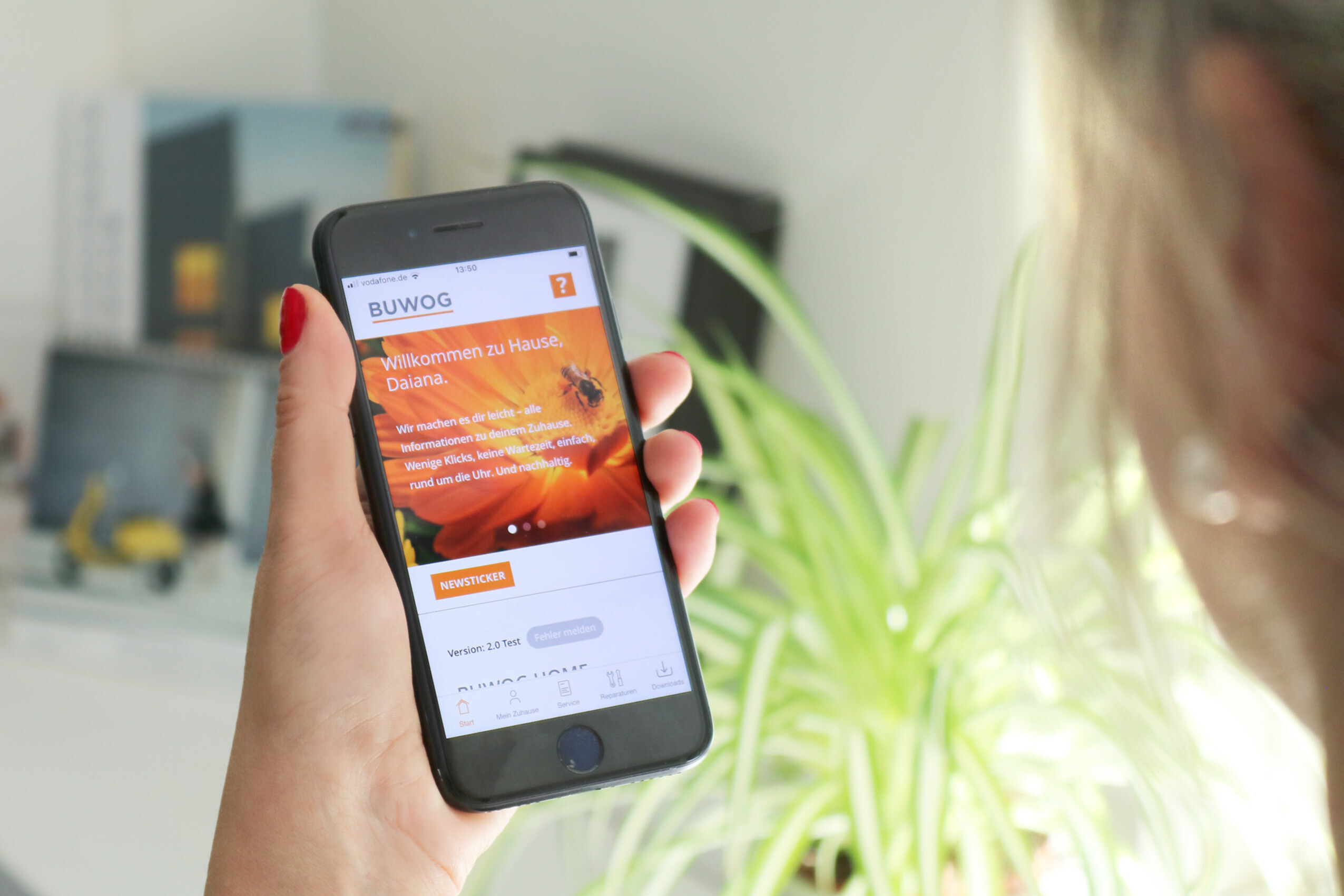 Eine Frau hält ein Mobiltelefon, auf dem Screen ist die BUWOG App zu sehen
